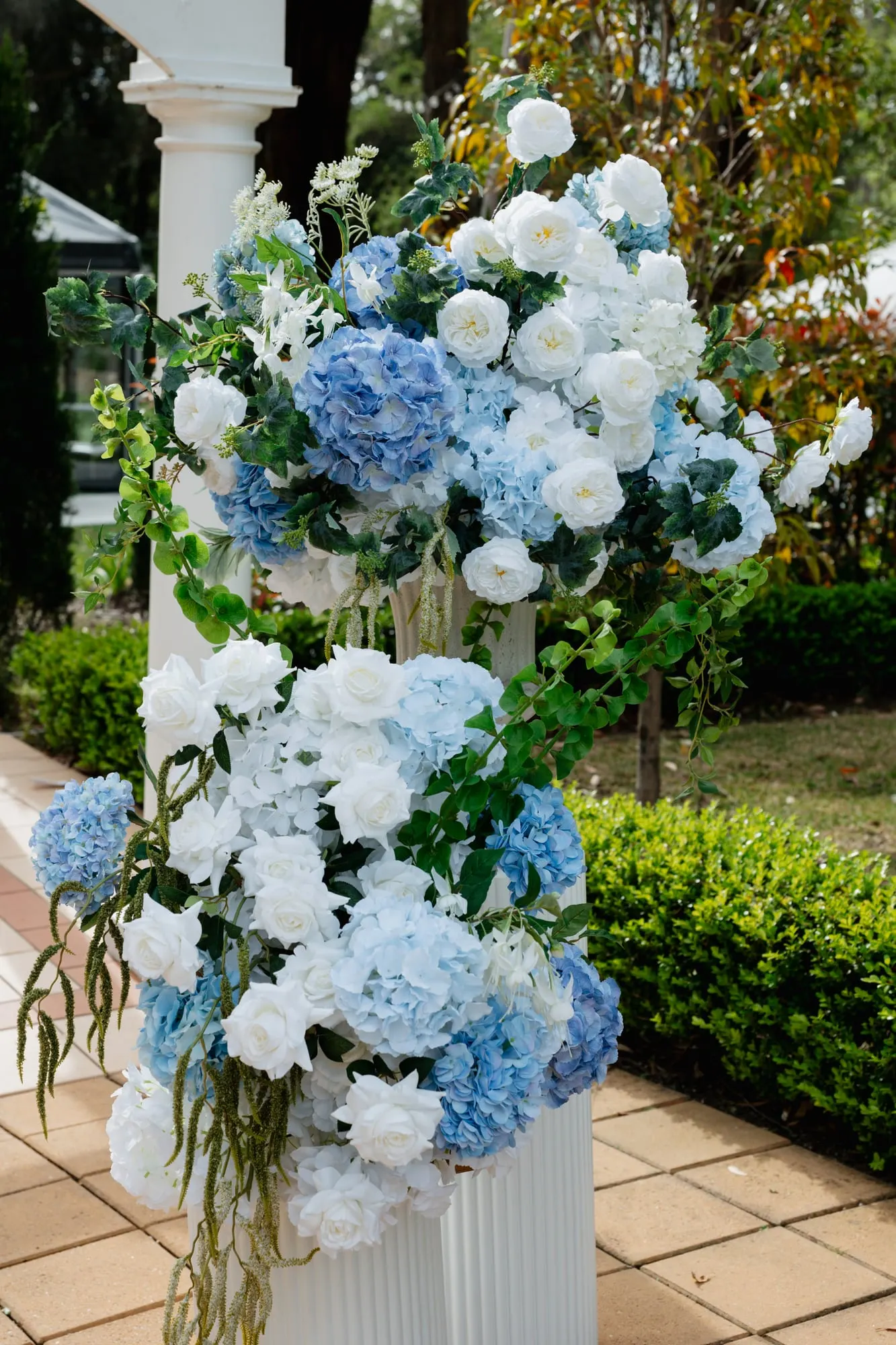 Blue and white hydrangea arrangement on a white plinth beside the aisle