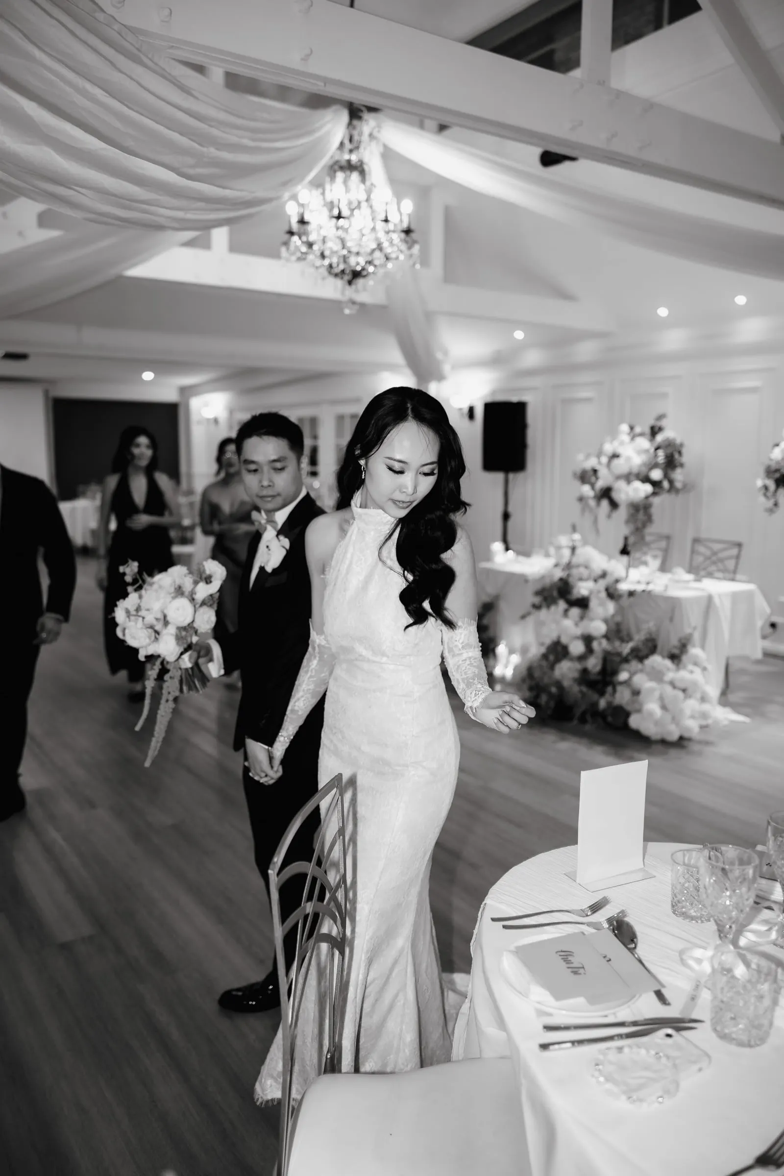 Black-and-white photo of the couple greeting guests in a styled reception room