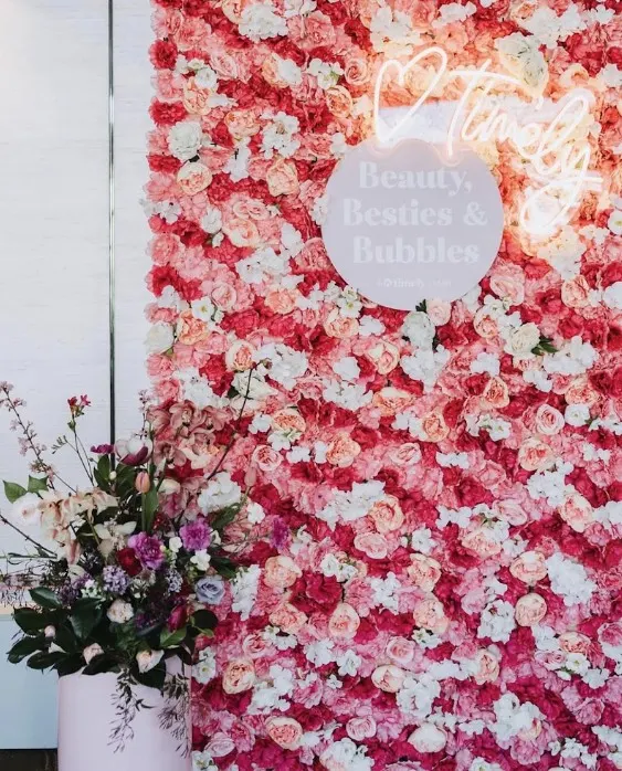 Pink and white flower wall with a neon sign, styled for a brand event
