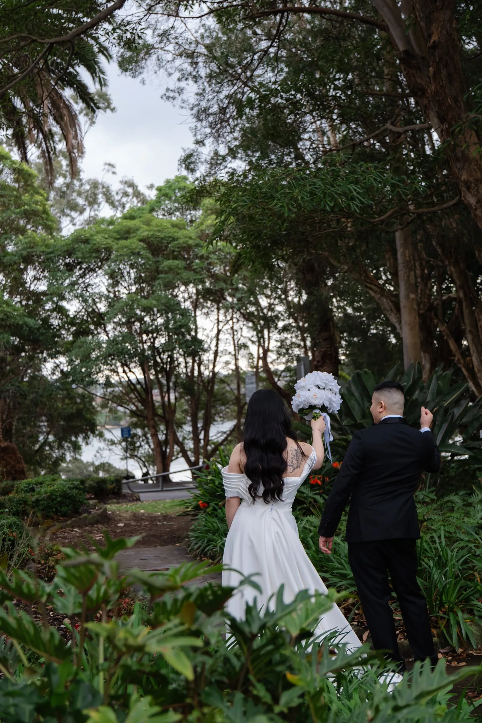 Bride and groom walking together through a leafy garden