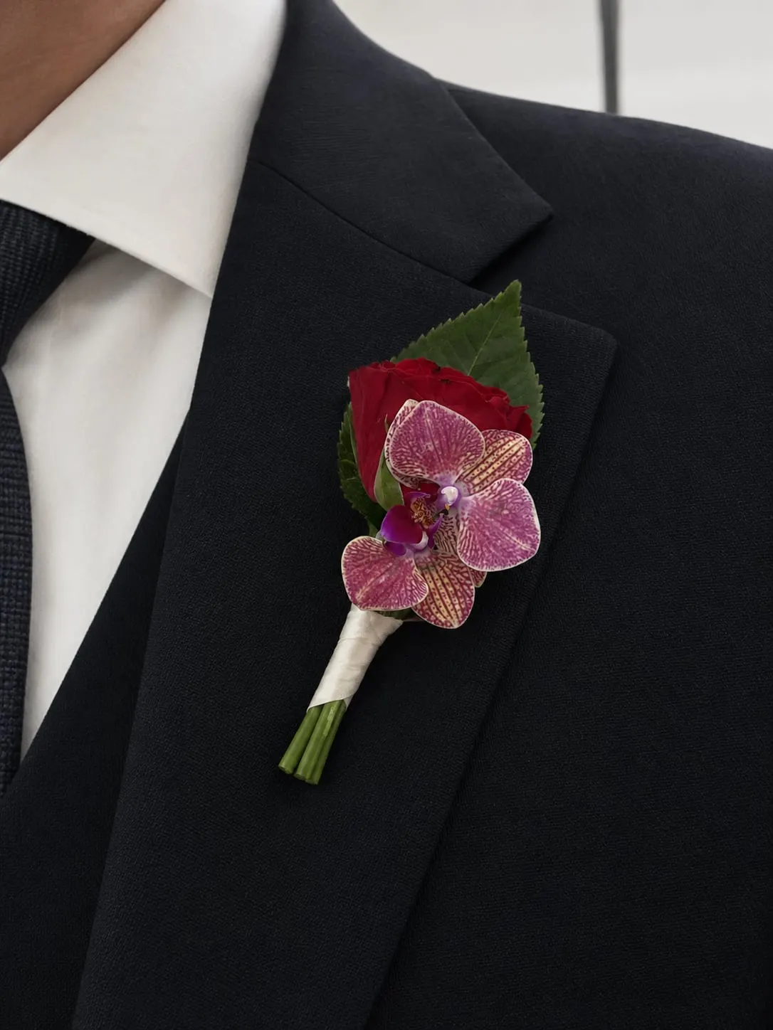 Pink orchid buttonhole on a black suit lapel
