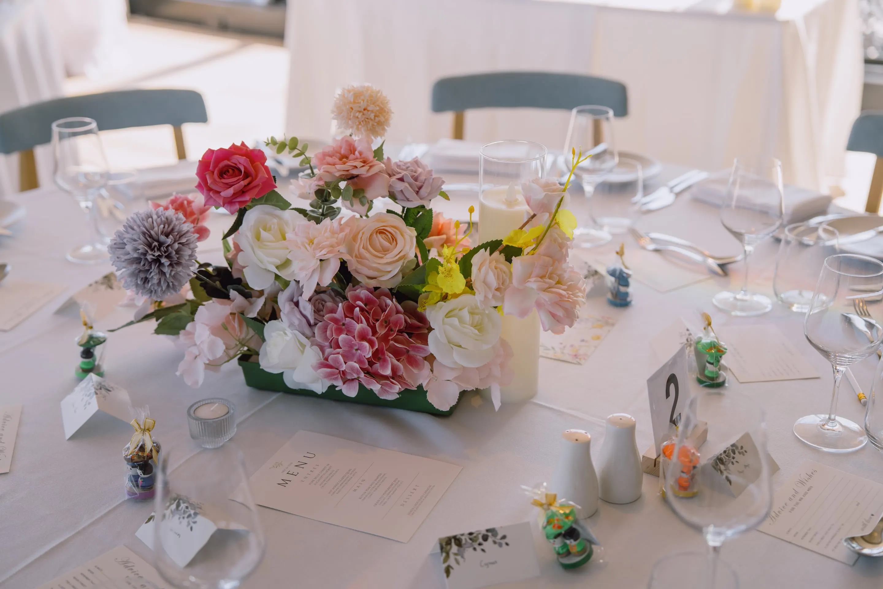 Pastel centrepiece of roses, dahlias and orchids on a set reception table