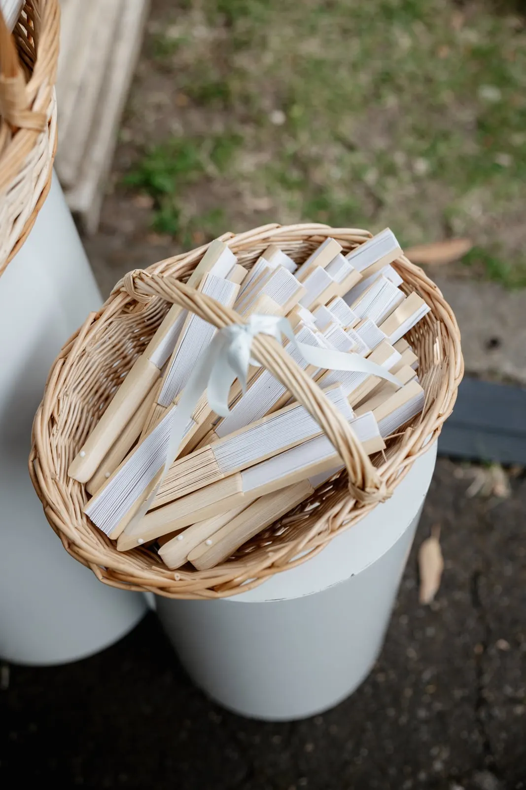Basket of white paper fans for guests at an outdoor ceremony