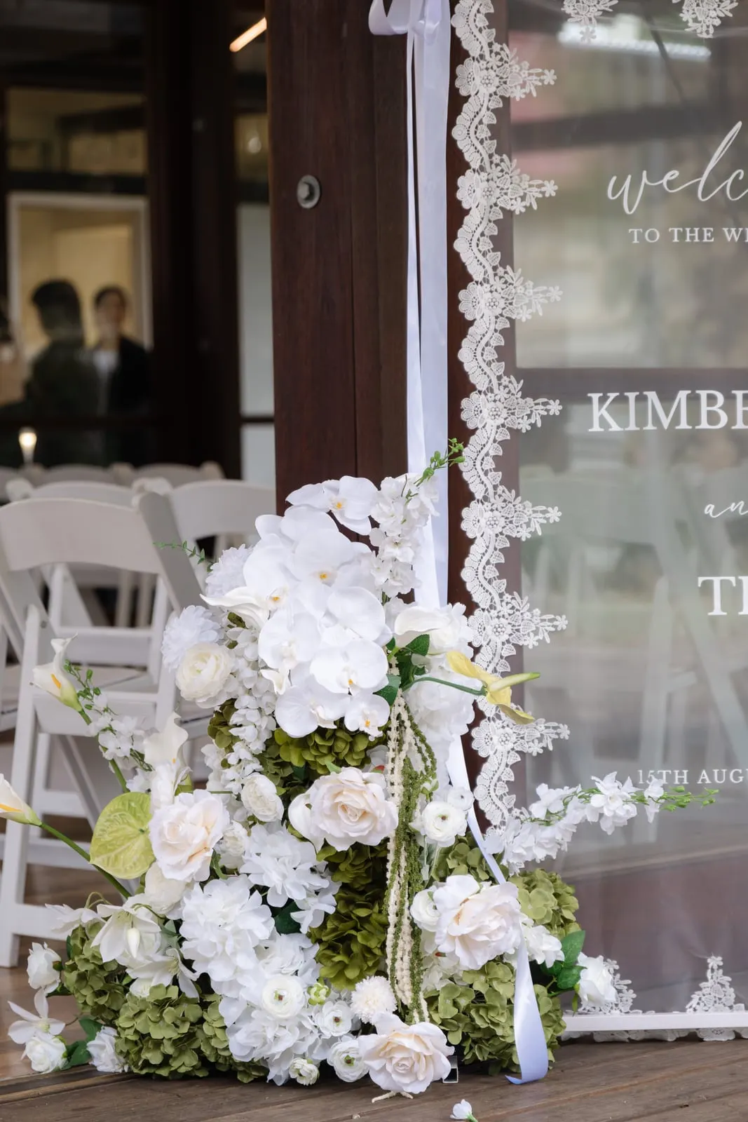 Welcome sign framed with white florals and greenery