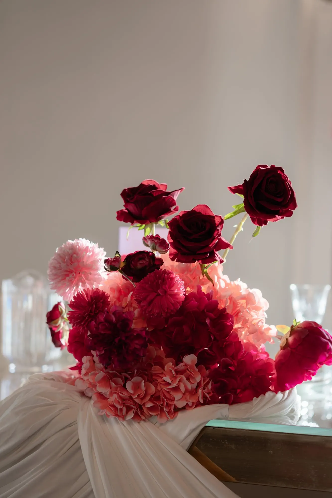 Arrangement of red roses, dahlias and pink blooms on a draped table
