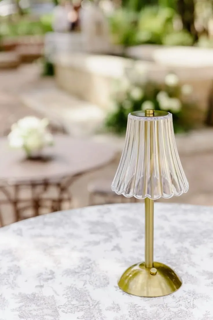 Gold table lamp with a ribbed glass shade on a floral tablecloth