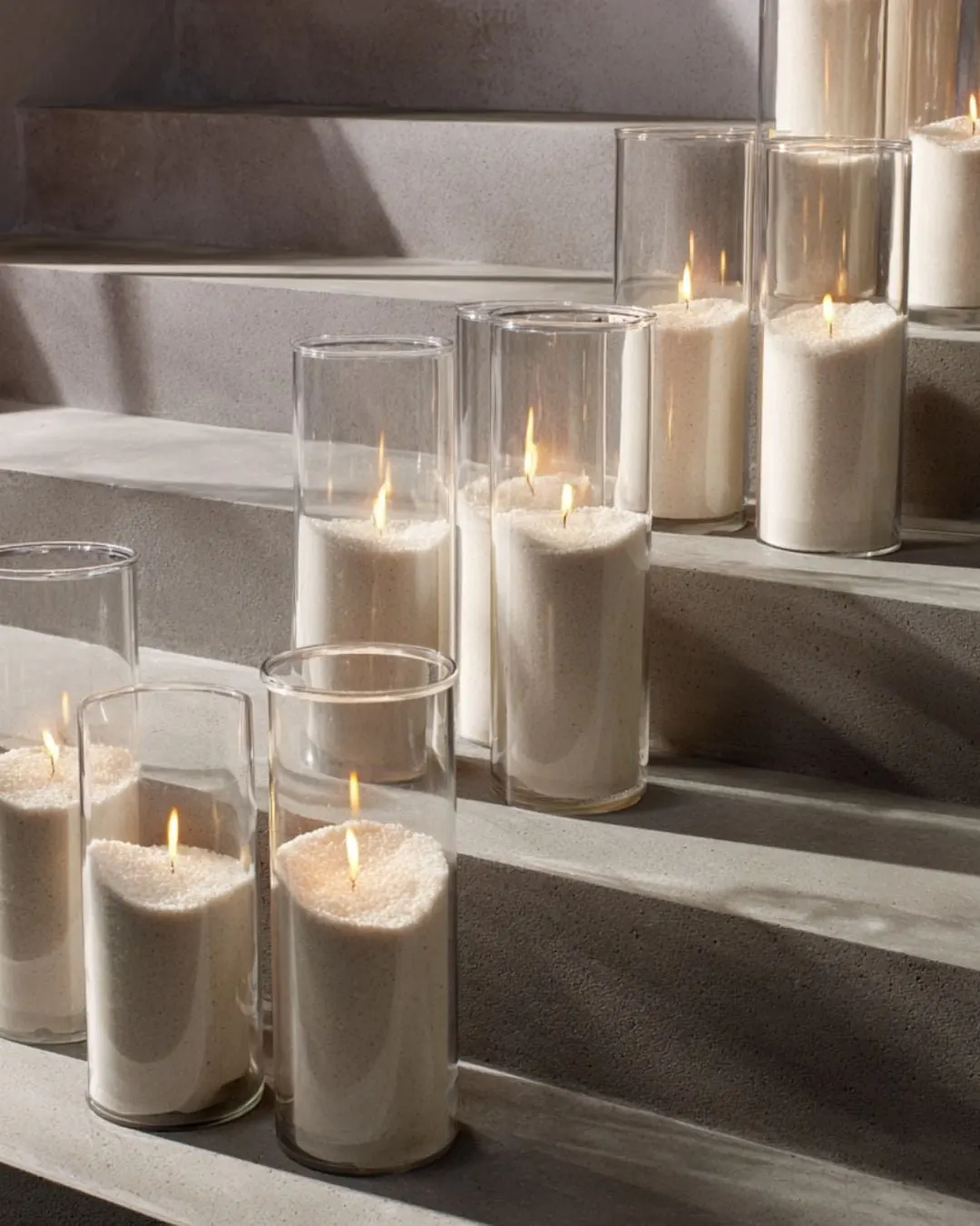 Pillar candles in tall glass cylinders glowing on stone steps