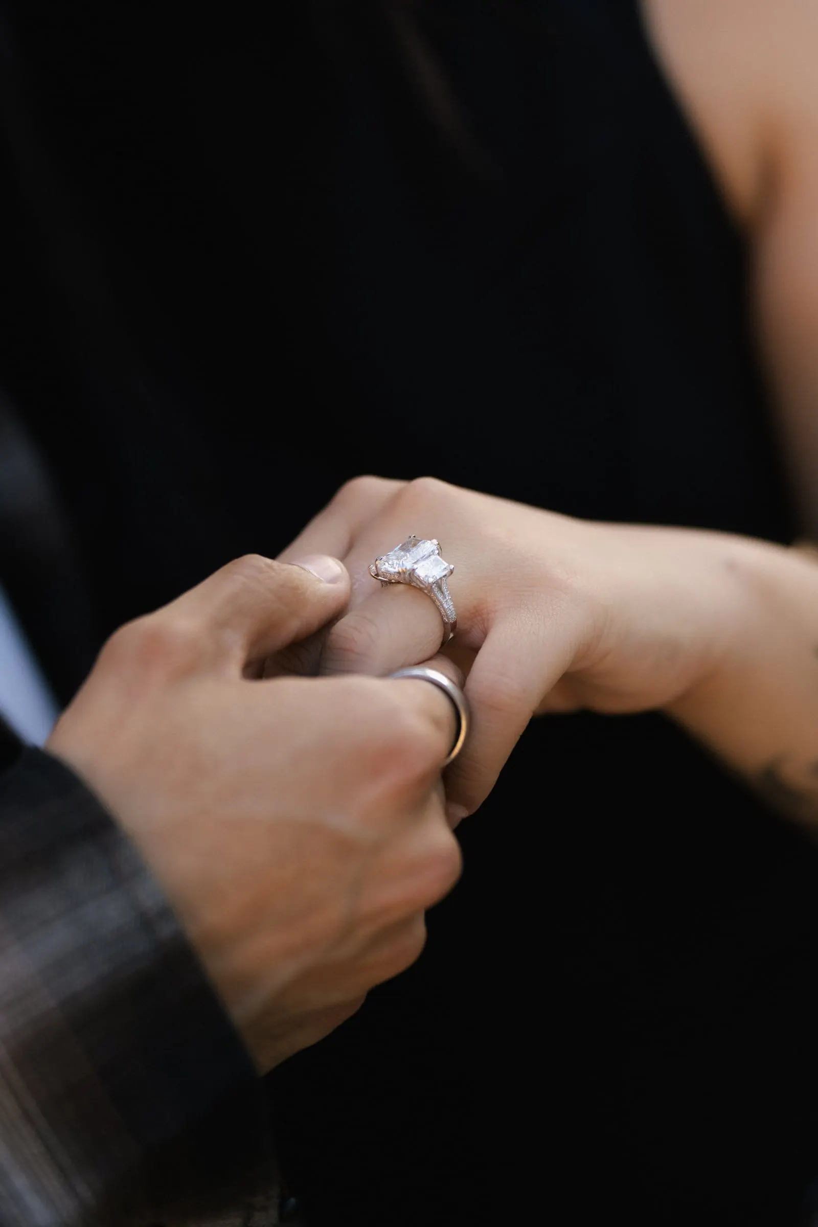 Close-up of a hand placing an engagement ring on a finger