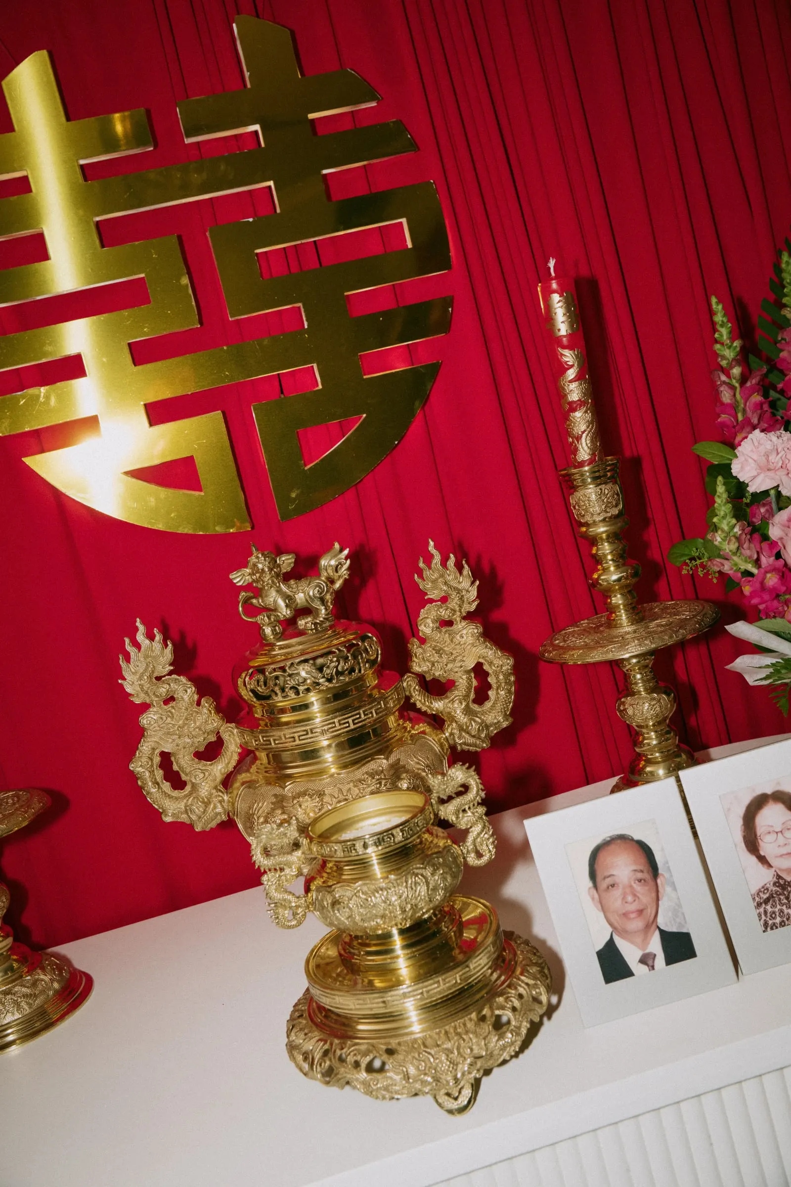 Gold double happiness sign above the family altar, with gold ornaments and framed family photos