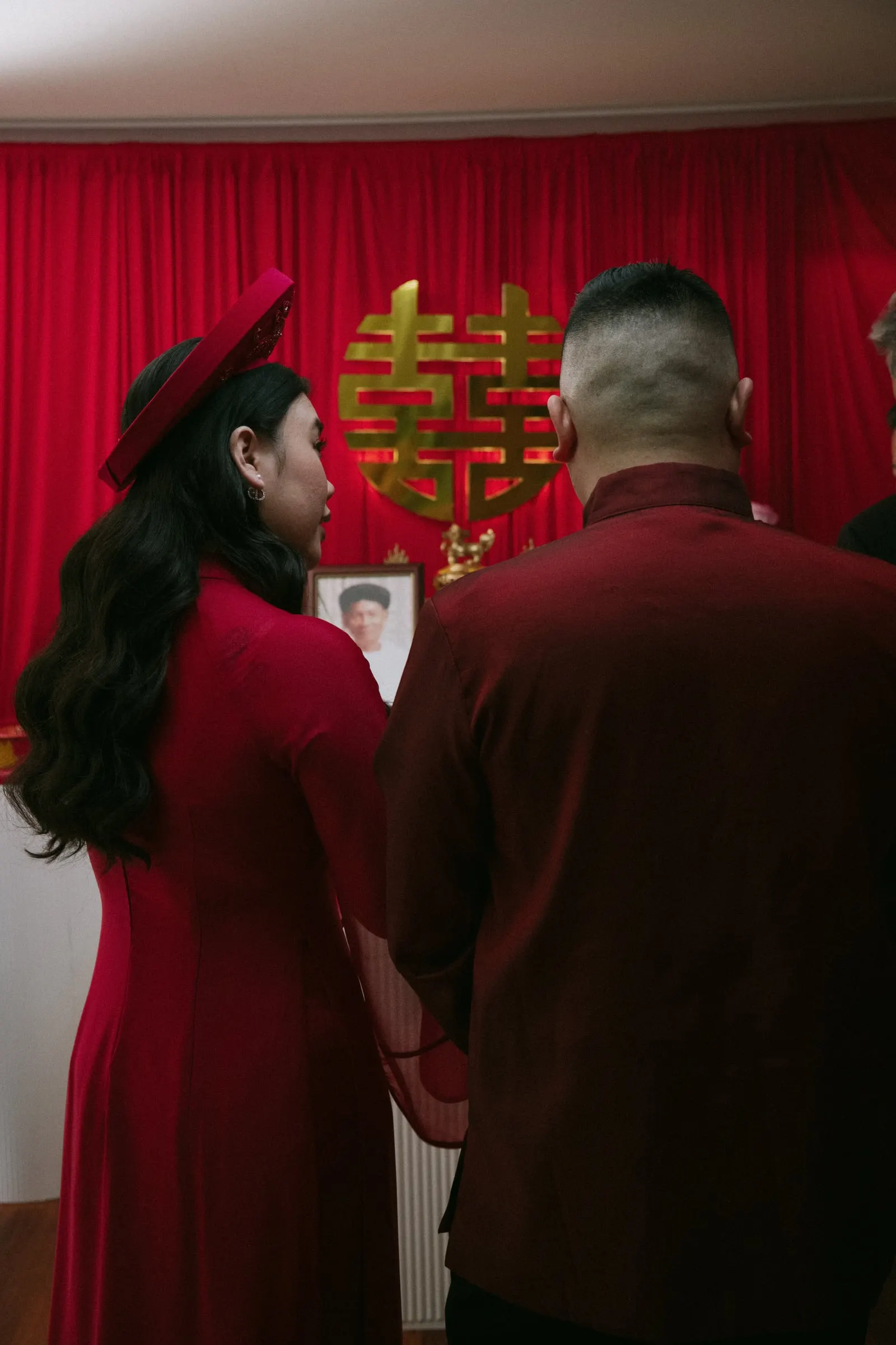 Couple in red traditional dress at the family altar during the tea ceremony