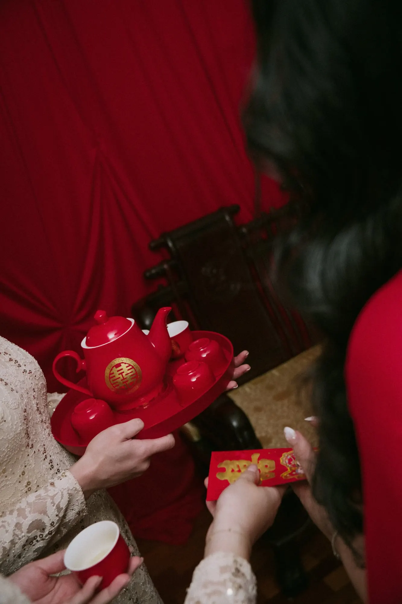 Hands holding red tea cups during the tea ceremony