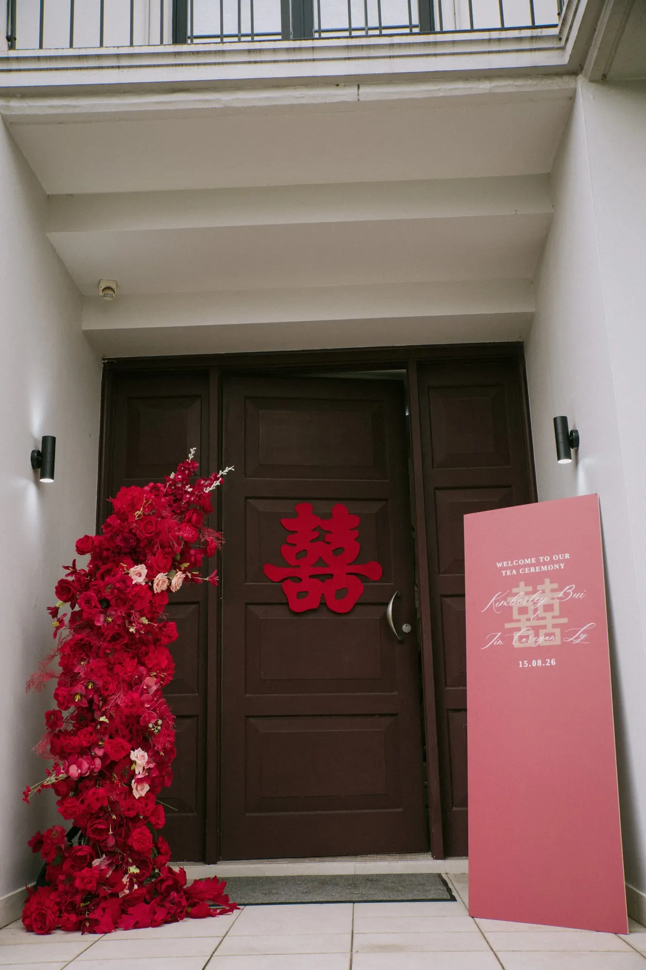 Front door with a red double happiness decal, a red rose cascade and a welcome sign