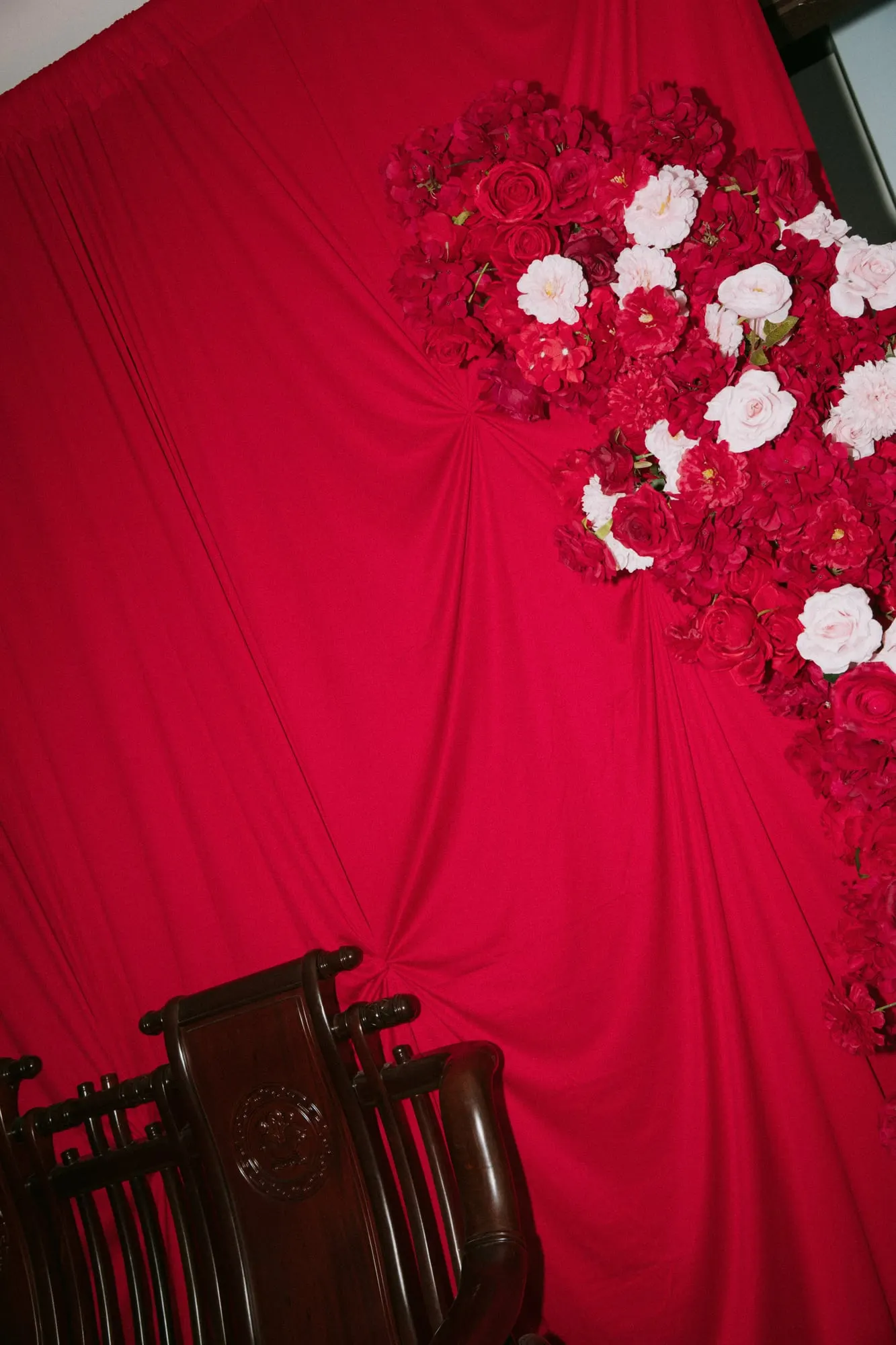 Red draped wall with rose florals in the corner