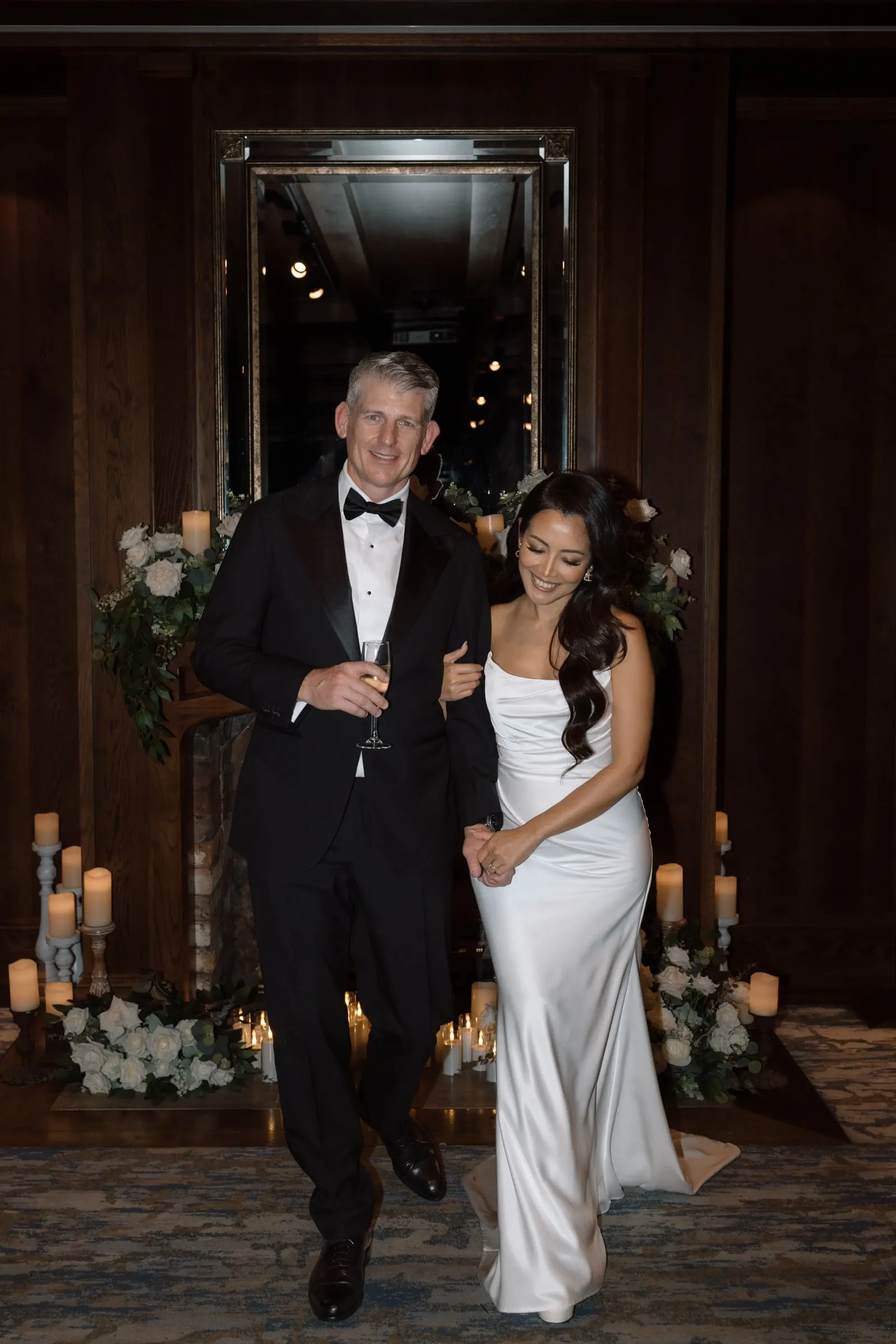 Newlyweds walking out arm in arm past candles and white florals
